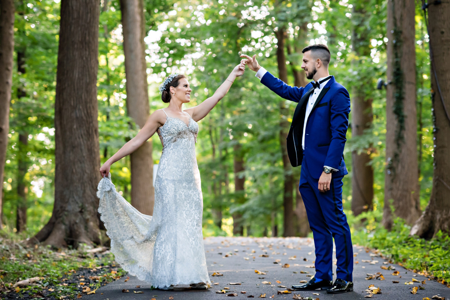 A bride spins around in her wedding dress for her husband in the middle of the forrest.